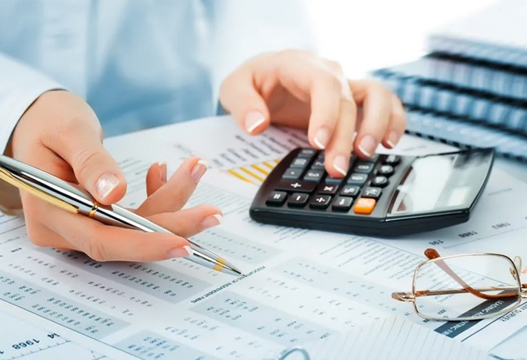 A student seeking help for an accounting complex assignment, using a calculator and pen to write on paper