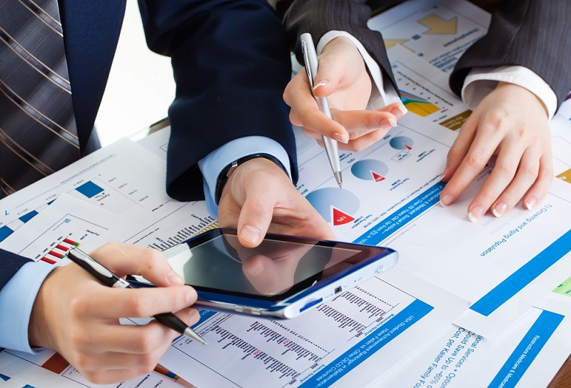 Two students in professional attire collaborating on a tablet for Banking Homework Help