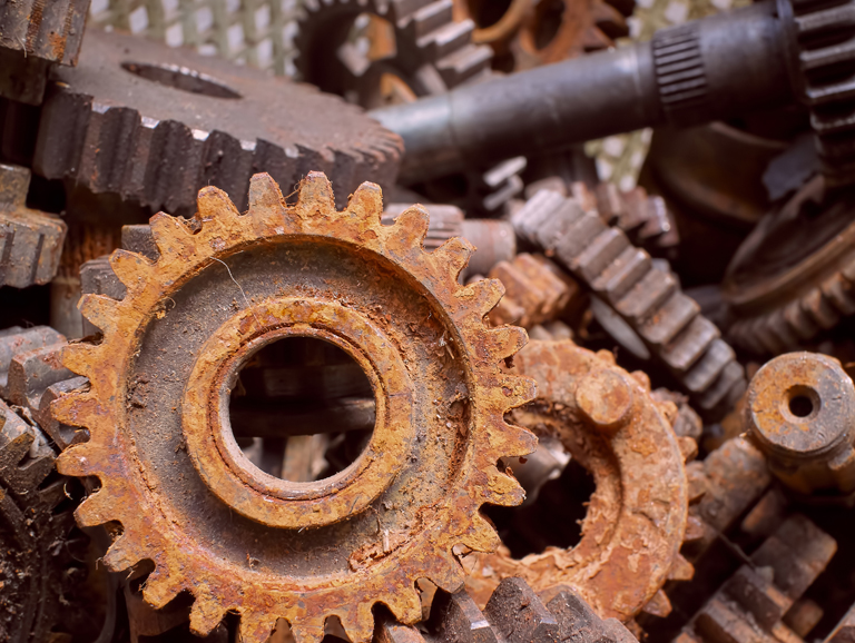 A pile of rusted gears and parts, showcasing corrosion. Seek assistance with your corrosion assignment