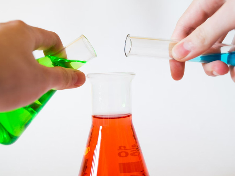 inorganic chemistry assignment being carried out by chemistry students, hands holding test tubes with coloured liquid