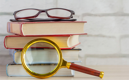  Books, glasses, and magnifying glass on wooden table - perfect setup for a literature review concept