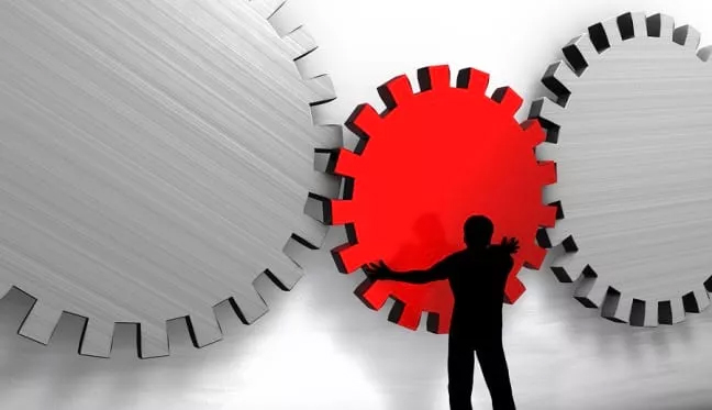 A man stands before a red gear wheel, representing the concept of operations management assignment help