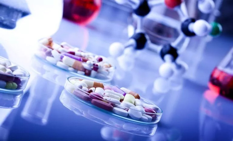 Many pills and tablets of various types arranged on a table representing a pharmaceutics homework help