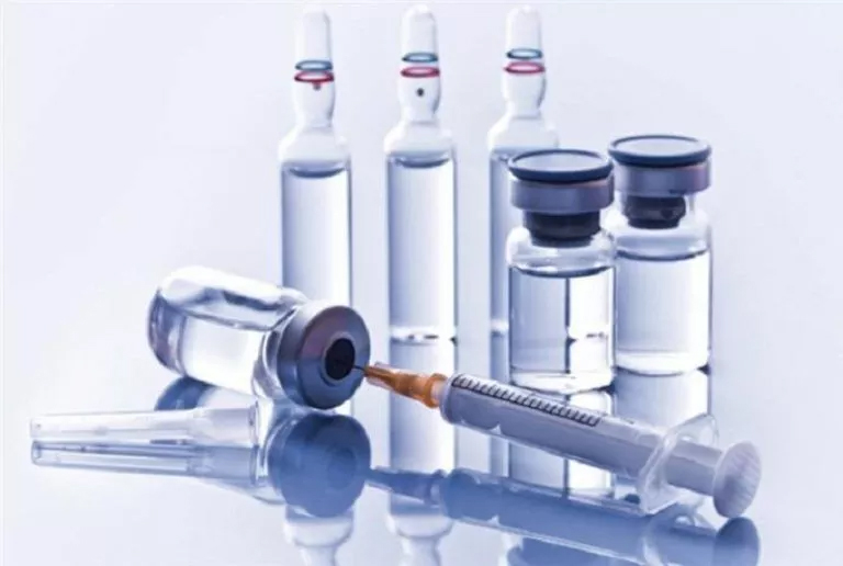 Vaccine vials and syringes neatly arranged on a table. Image depicts pharmacy homework help