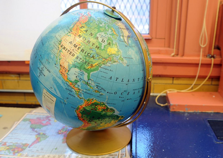 A globe on a desk in a classroom, symbolizing social studies homework and assignment help.